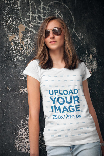 Mockup of a Young Woman Wearing a T-Shirt and Leaning against an Urban Wall 2759-el1