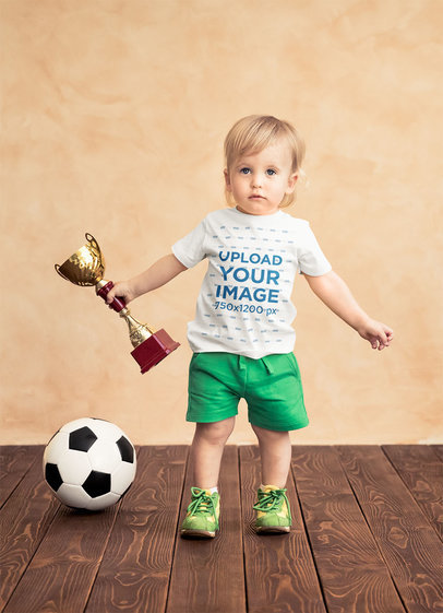 Download Placeit T Shirt Mockup Of A Baby Boy Holding A Soccer Trophy